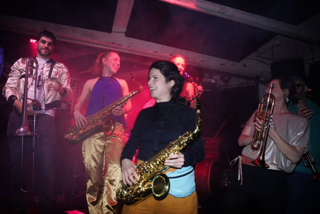 Photograph of a brass band playing on a stage at a club concert